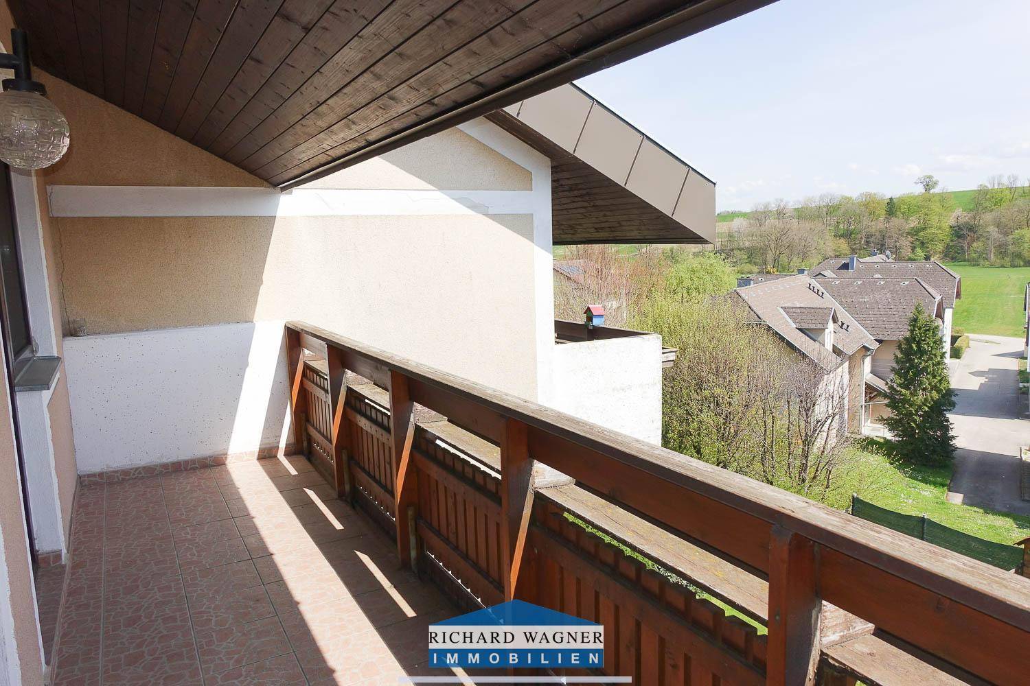 Balkon mit schöner Aussicht auf die grüne Umgebung und die Nachbarschaft.