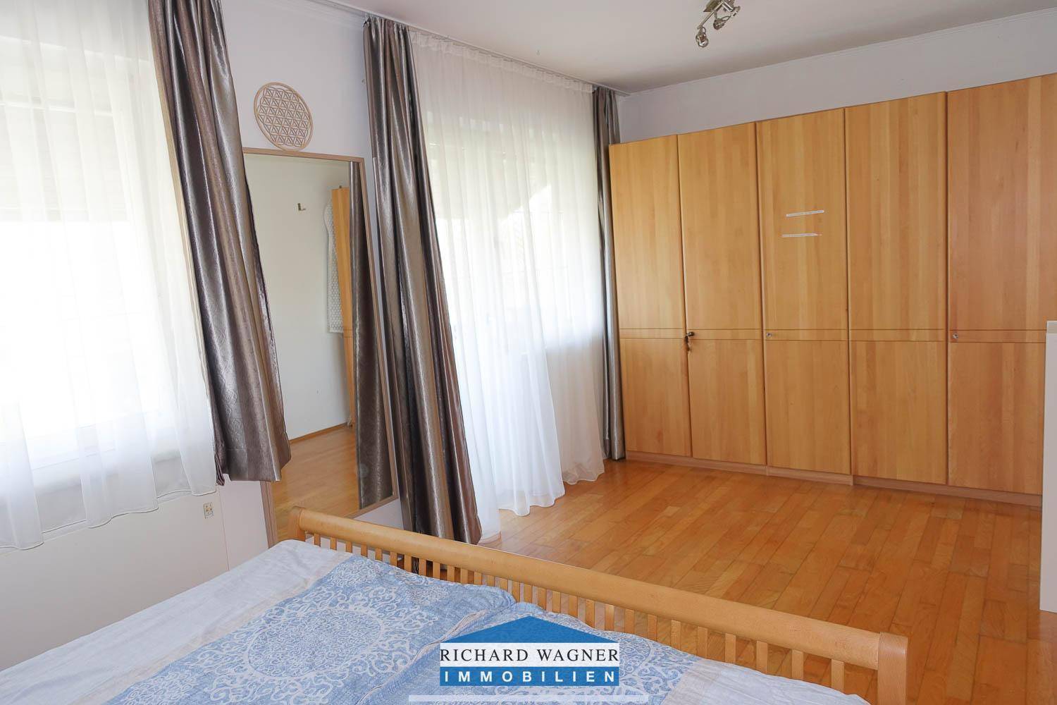 Schlafzimmer mit großem Holzbett, geräumigem Kleiderschrank und viel Tageslicht.