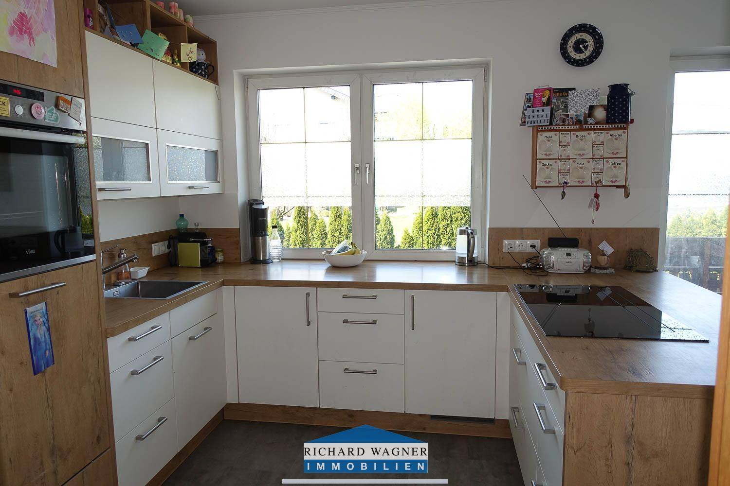 Funktionale Küche mit Arbeitsflächen, Spüle und Fenster mit Blick ins Grüne.