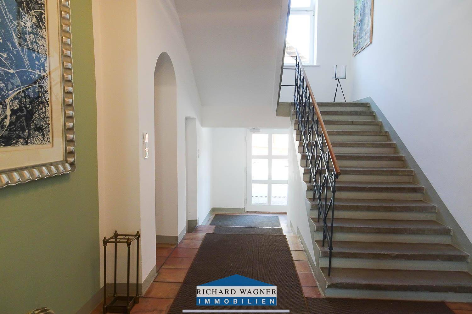Treppenhaus mit Steinstufen und schmiedeeisernem Geländer, das zu den oberen Stockwerken führt.