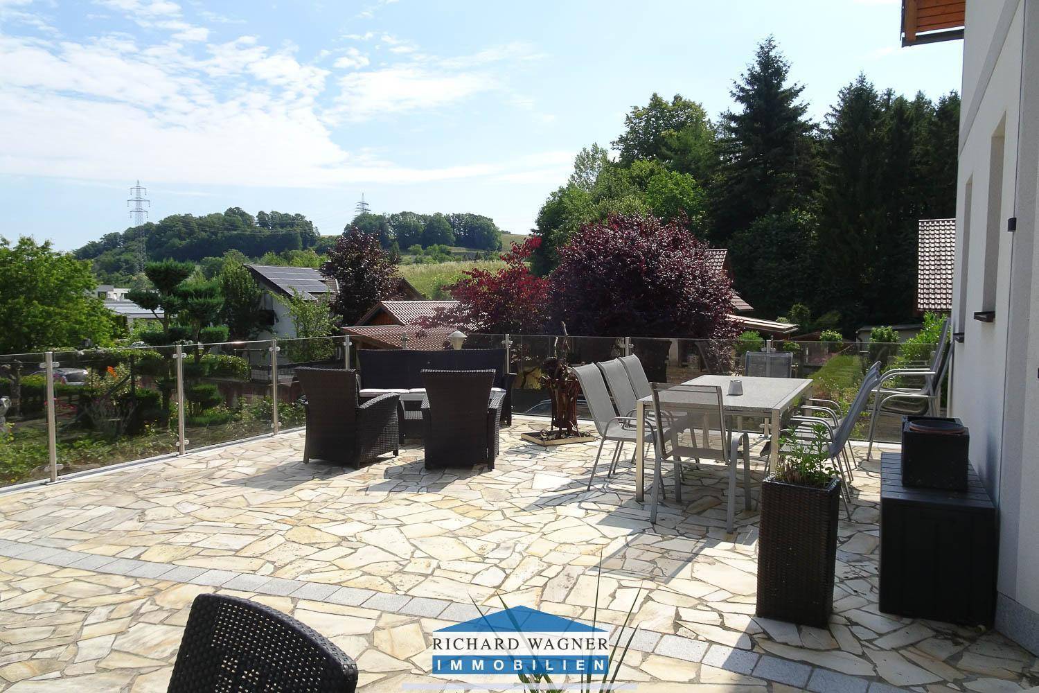 Geräumige Terrasse mit modernen Outdoor-Möbeln und weitem Blick über die grüne Landschaft.
