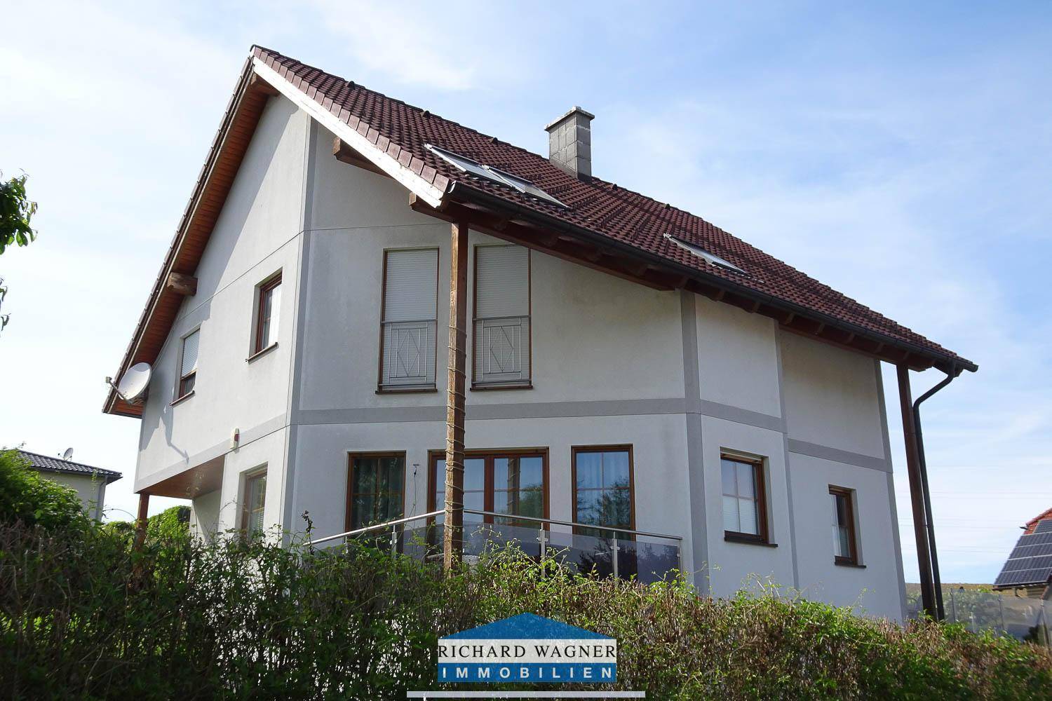 Ansicht des Einfamilienhauses mit Satteldach, Dachfenstern und einem kleinen französischen Balkon.