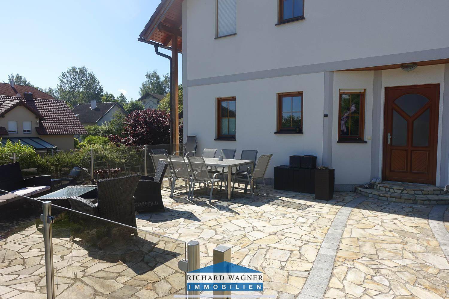 Große gepflasterte Terrasse mit Sitzgelegenheiten und einem Esstisch, ideal für Mahlzeiten im Freien.