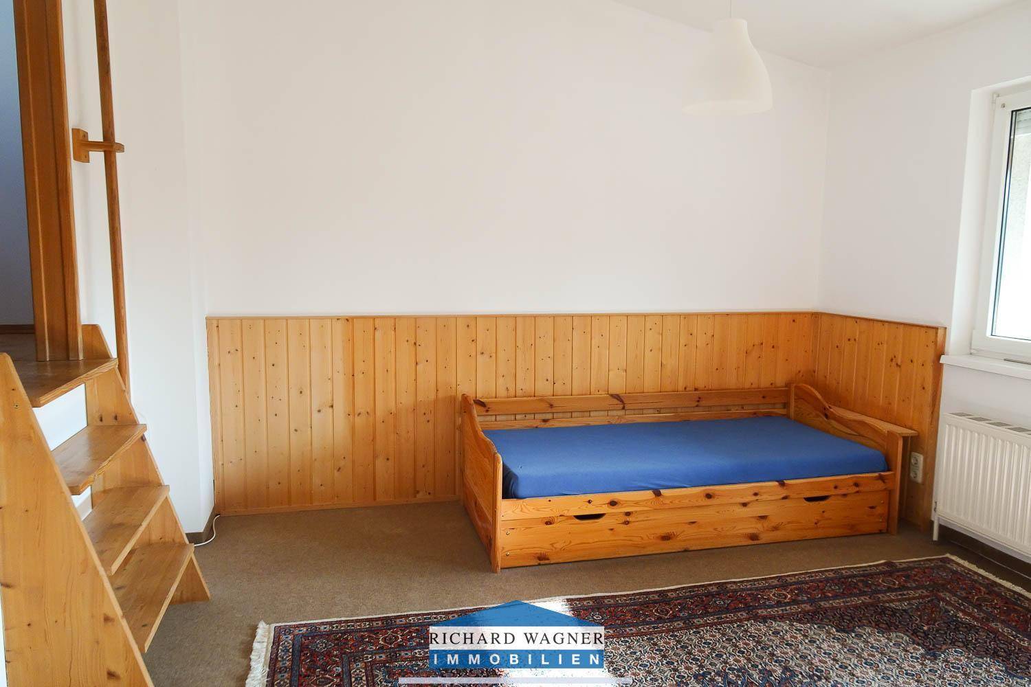 Schlafzimmer oder Gästezimmer mit Holz-Tagesbett, Holzvertäfelung und Fenster.