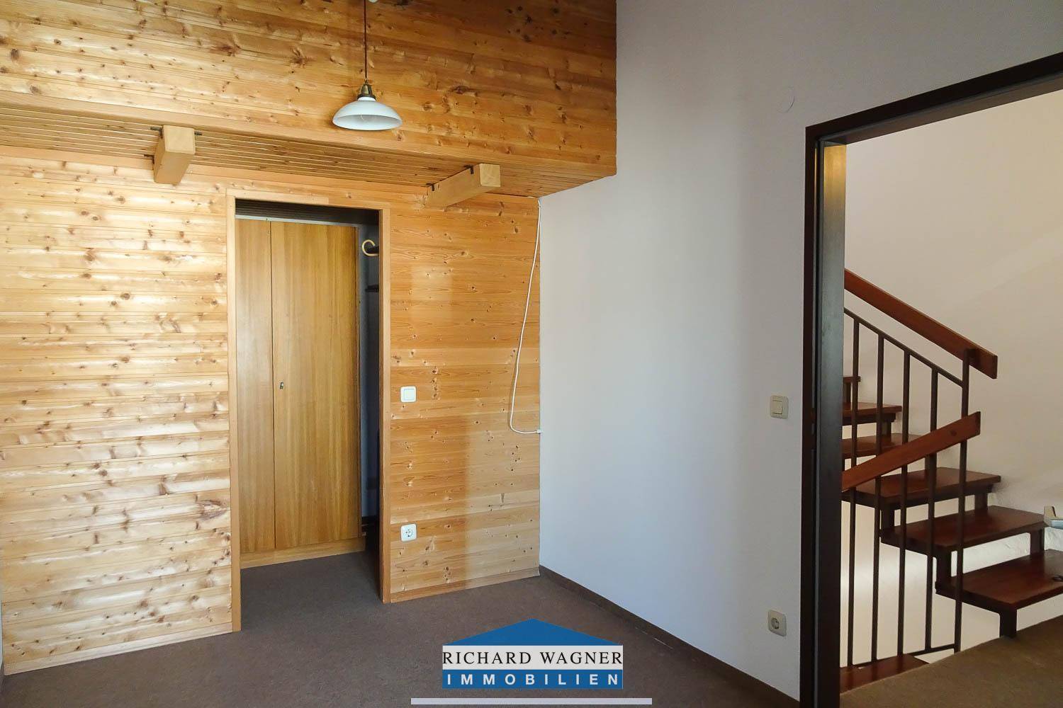 Zimmer mit umfassender Holzvertäfelung an Wänden und Decke, sowie einem Türrahmen.