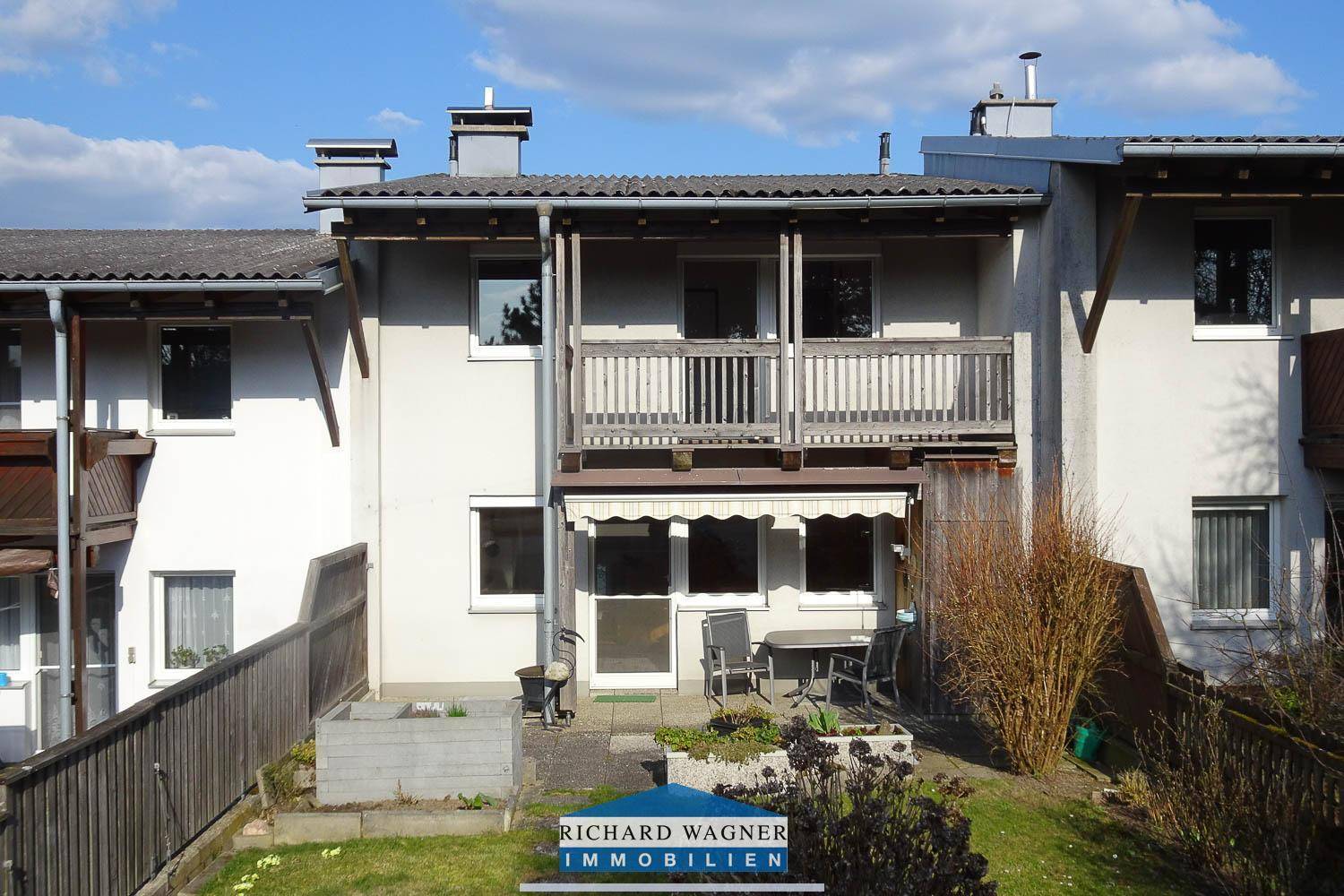 Rückansicht des Hauses mit Balkon im Obergeschoss und einer Terrasse mit Gartenbereich.