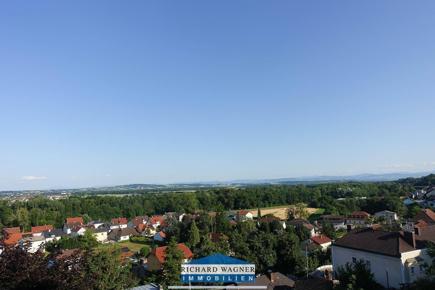 Weitläufiger Panoramablick über die ländliche Umgebung mit Wäldern und Siedlungen unter blauem Himmel.