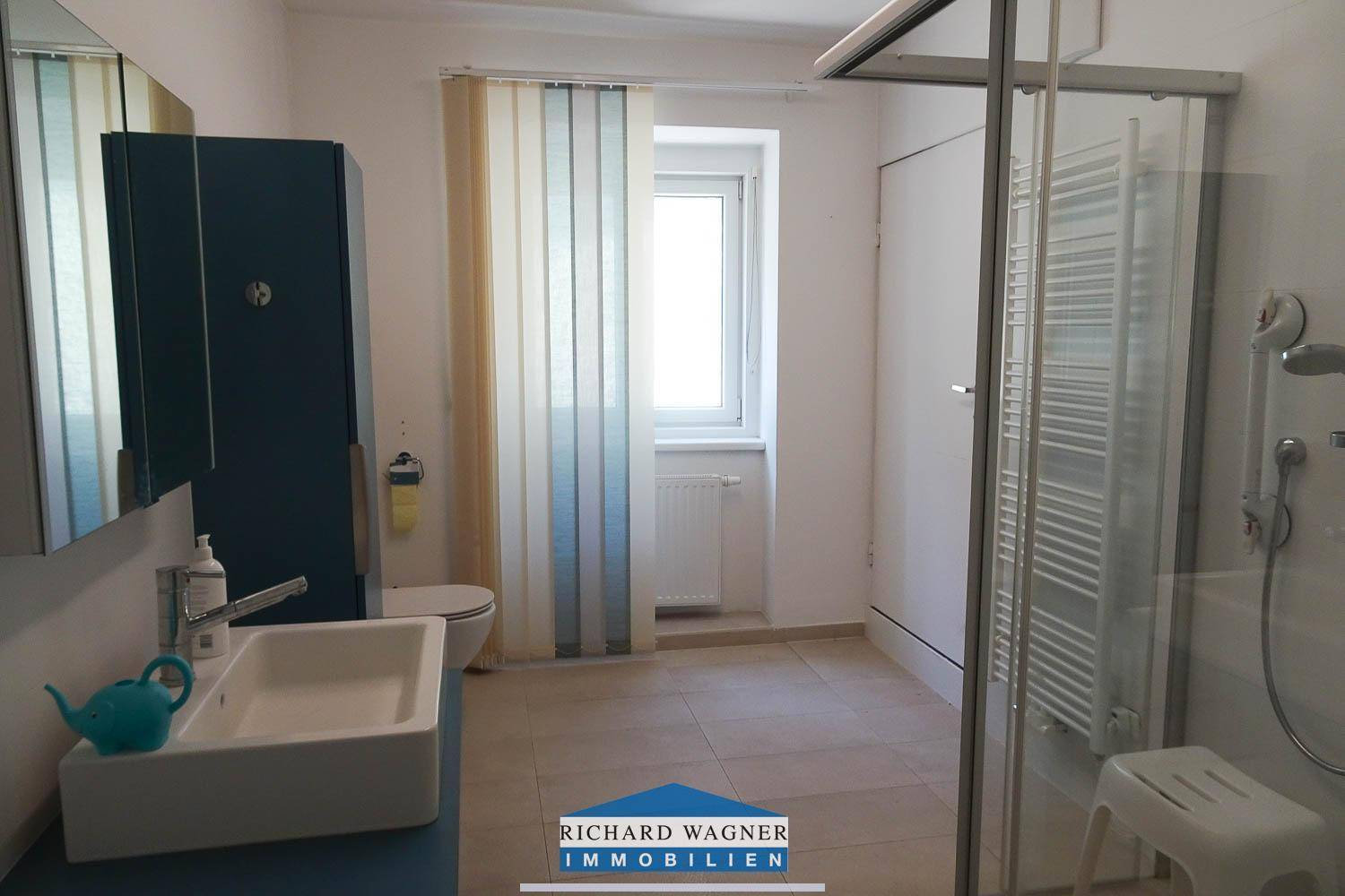 Modernes Badezimmer mit Dusche, WC, Waschbecken und beheiztem Handtuchhalter.