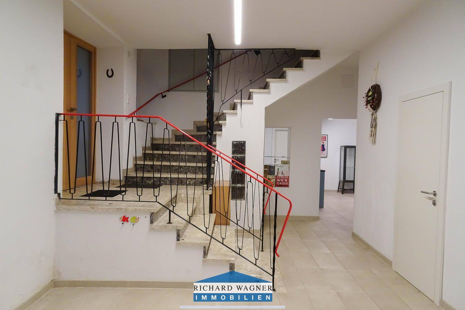 Geräumiger Flur mit Marmorboden und einer geschwungenen Treppe mit schmiedeeisernem Geländer.