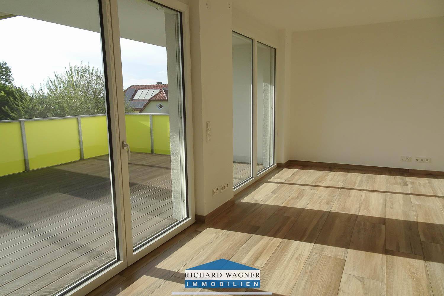 Lichtdurchfluteter Wohnbereich mit Holzboden und direktem Zugang zu einem sonnigen Balkon.