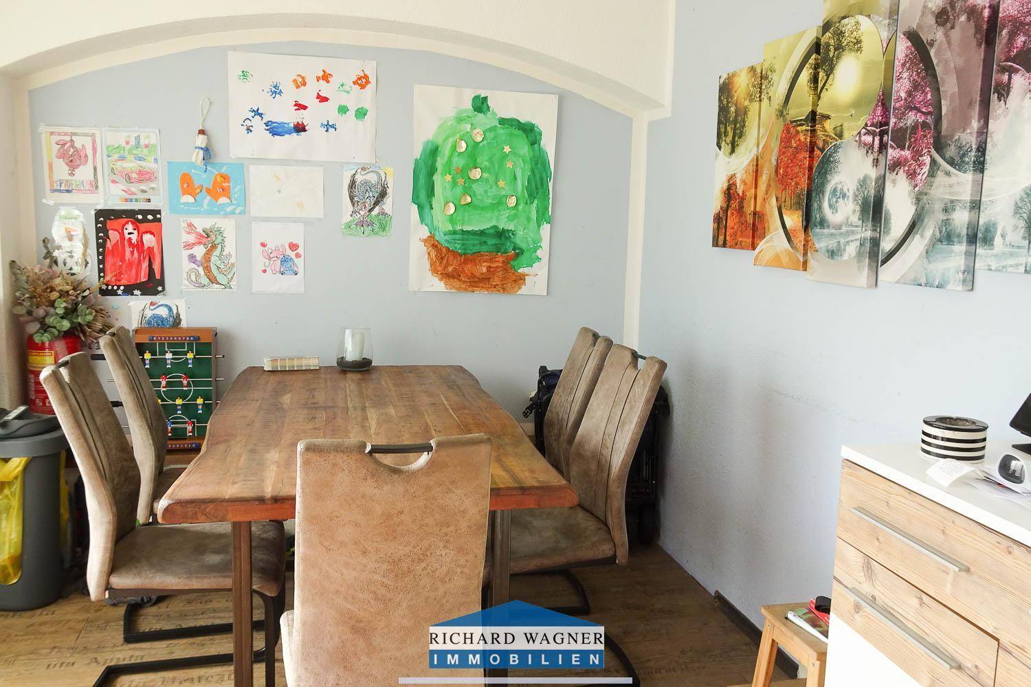 Gemütlicher Essbereich mit großem Holztisch und kreativer Wanddekoration.