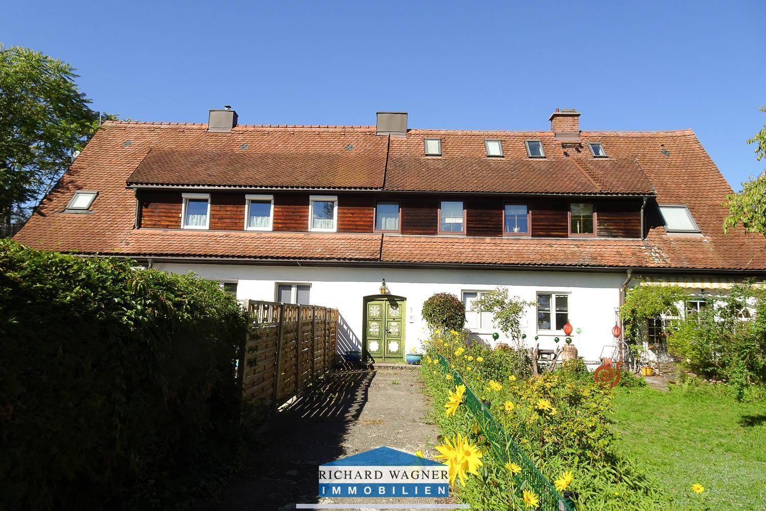 Vorderansicht des Hauses mit traditioneller Fassade, grüner Eingangstür und Vorgarten.