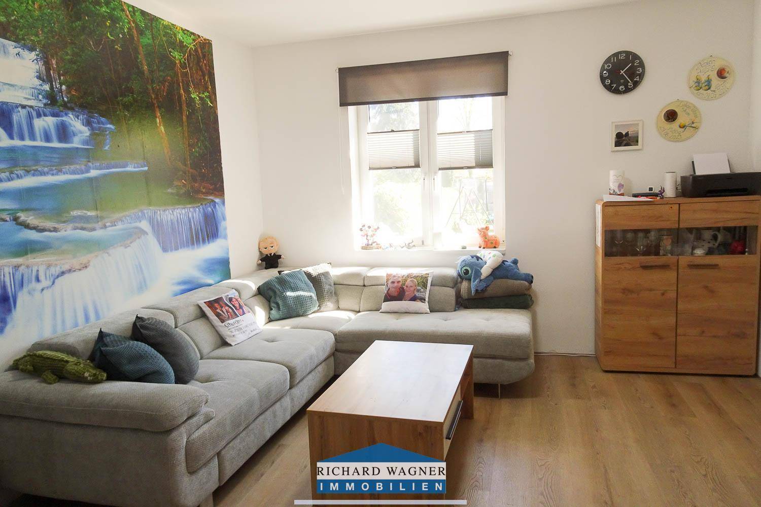 Helles Wohnzimmer mit großem Sofa, Holztisch und dekorativer Wasserfall-Tapete.
