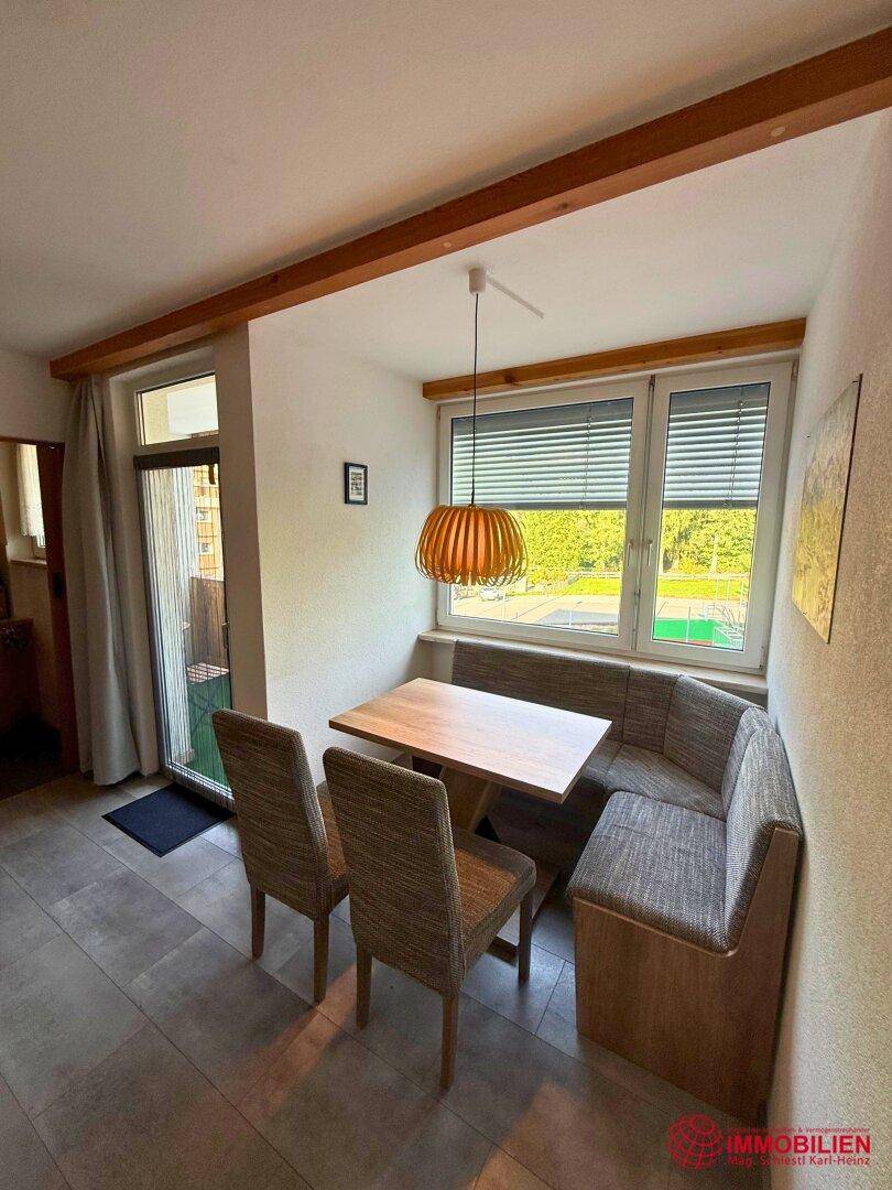 Gemütliche Essecke mit Sitzbank, Holztisch und Zugang zum Balkon.