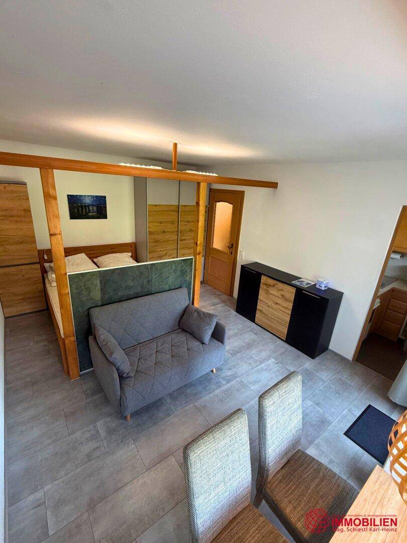 Kombinierter Wohn- und Schlafbereich mit Sofa, Bett und modernem Fliesenboden.