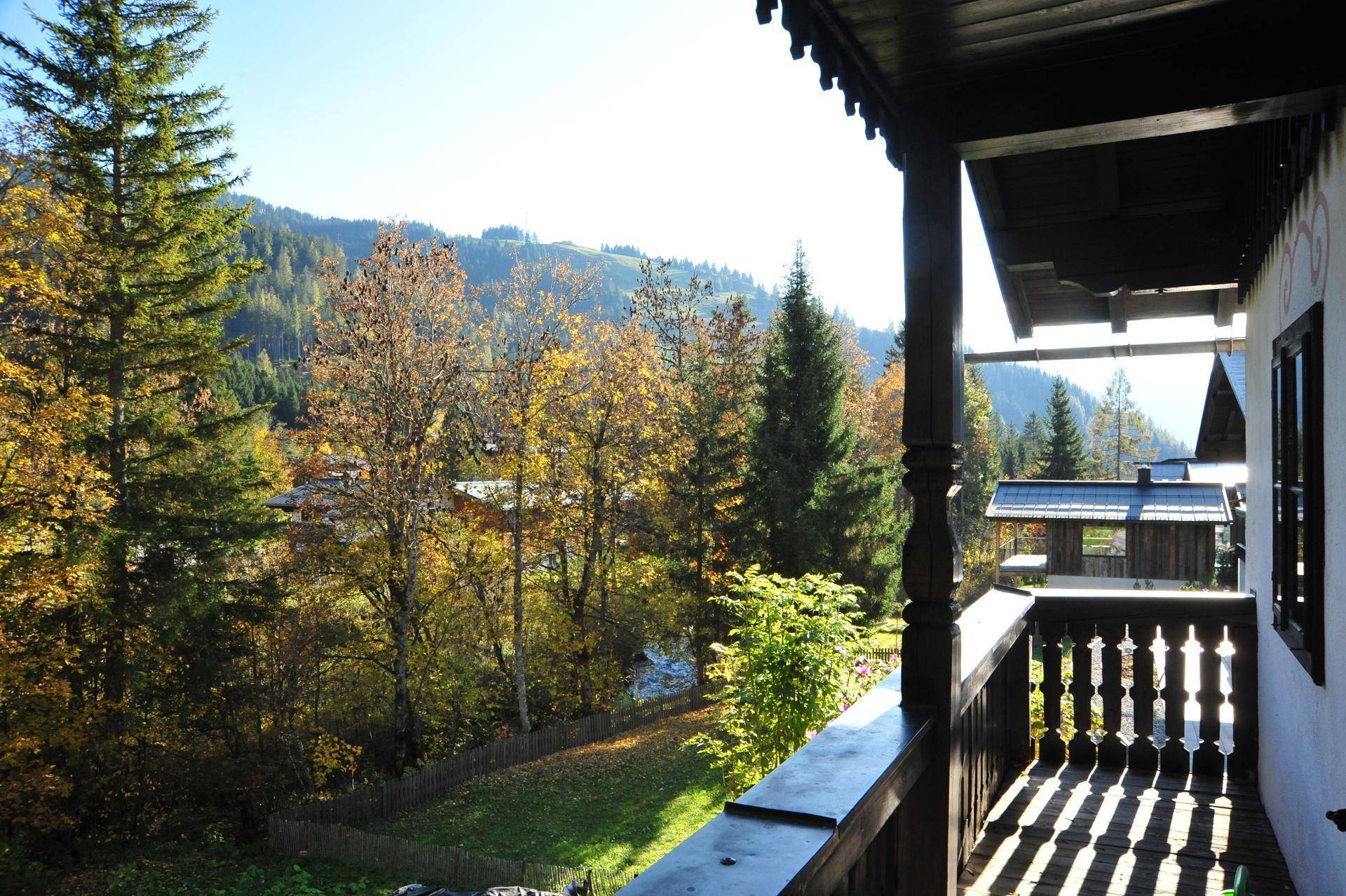 Sonniger Balkon mit Holzbalken und weitem Blick auf die grüne Berglandschaft.