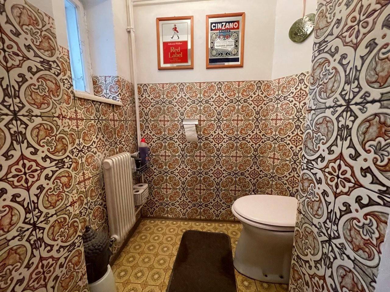 Kleines Gäste-WC mit auffälligen Fliesen und Fenster.