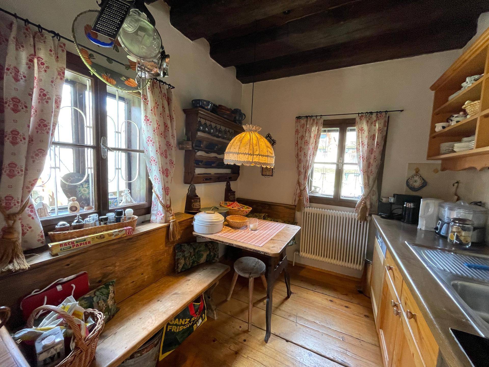 Gemütliche Essecke in der Küche mit Holzbänken, Holzboden und Fensterblick.