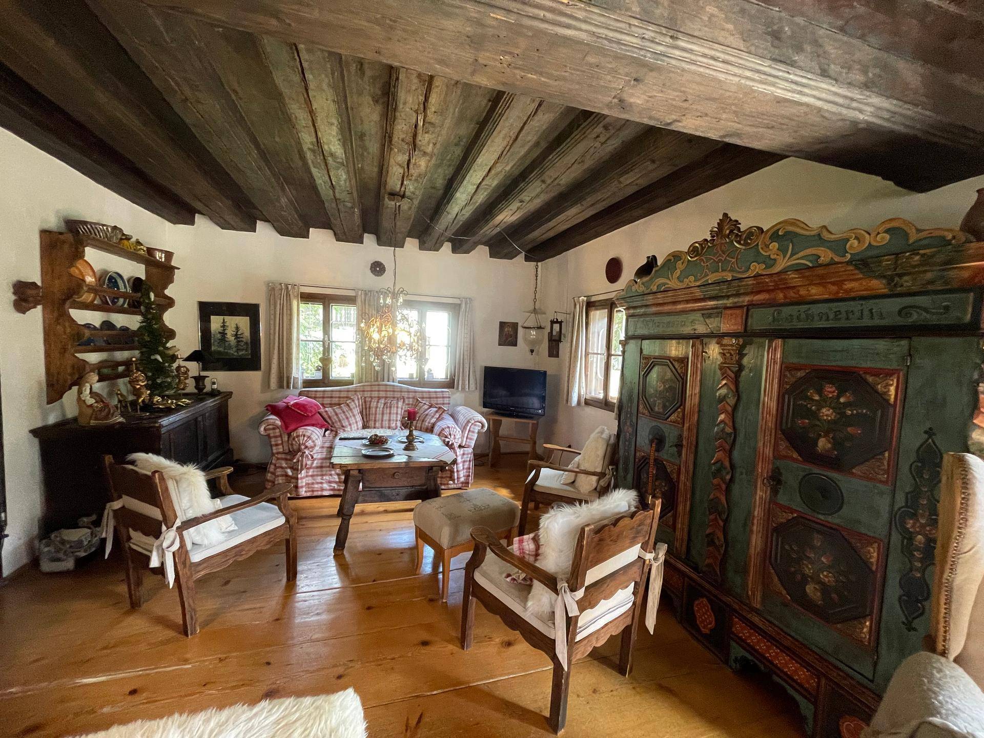 Gemütliches Wohnzimmer im Landhausstil mit Holzbalkendecke, Holzboden und traditionellen Möbeln.