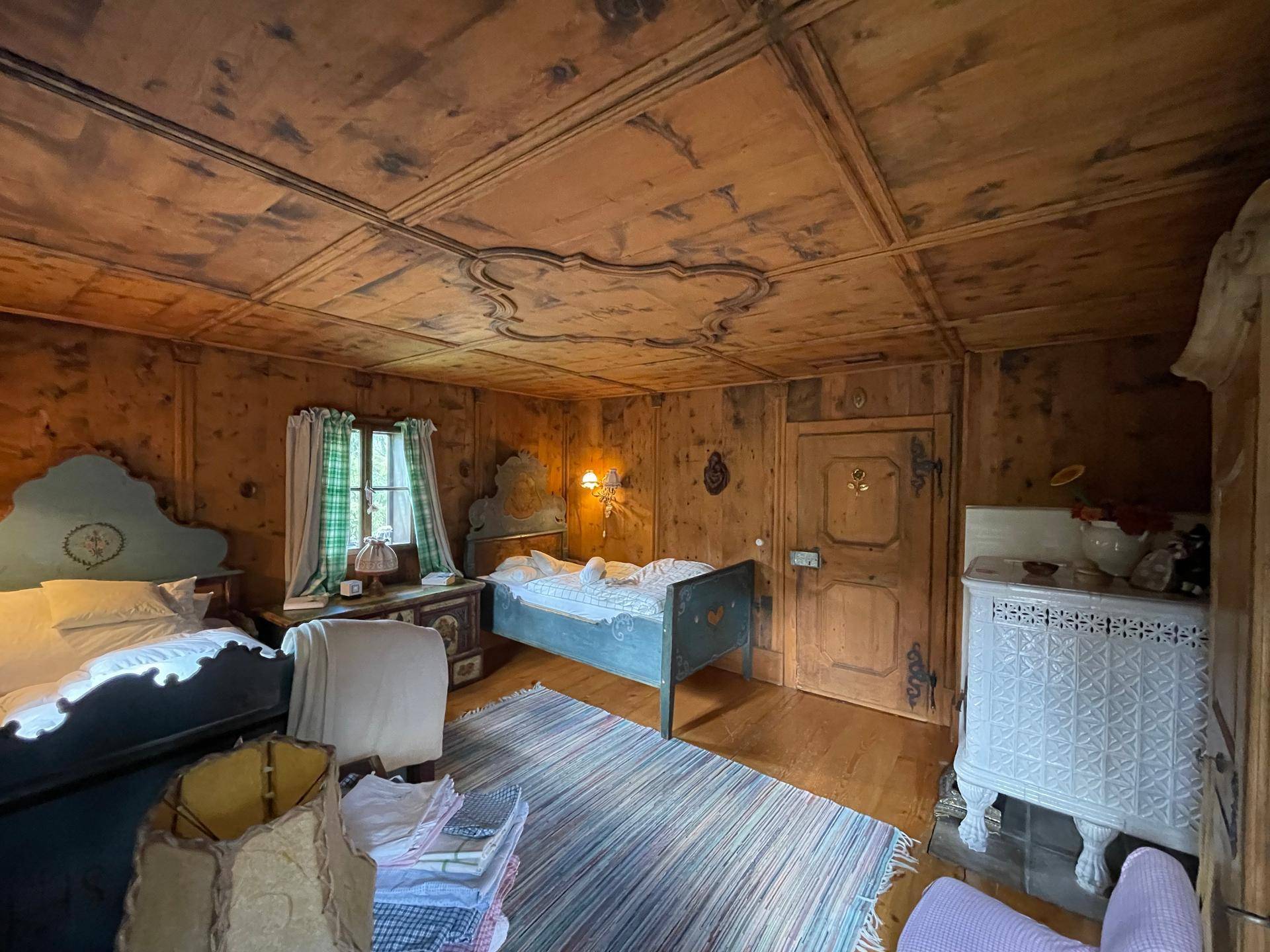Schlafzimmer im Landhausstil mit Holztäfelung, zwei Betten und einer verzierten Holzdecke.