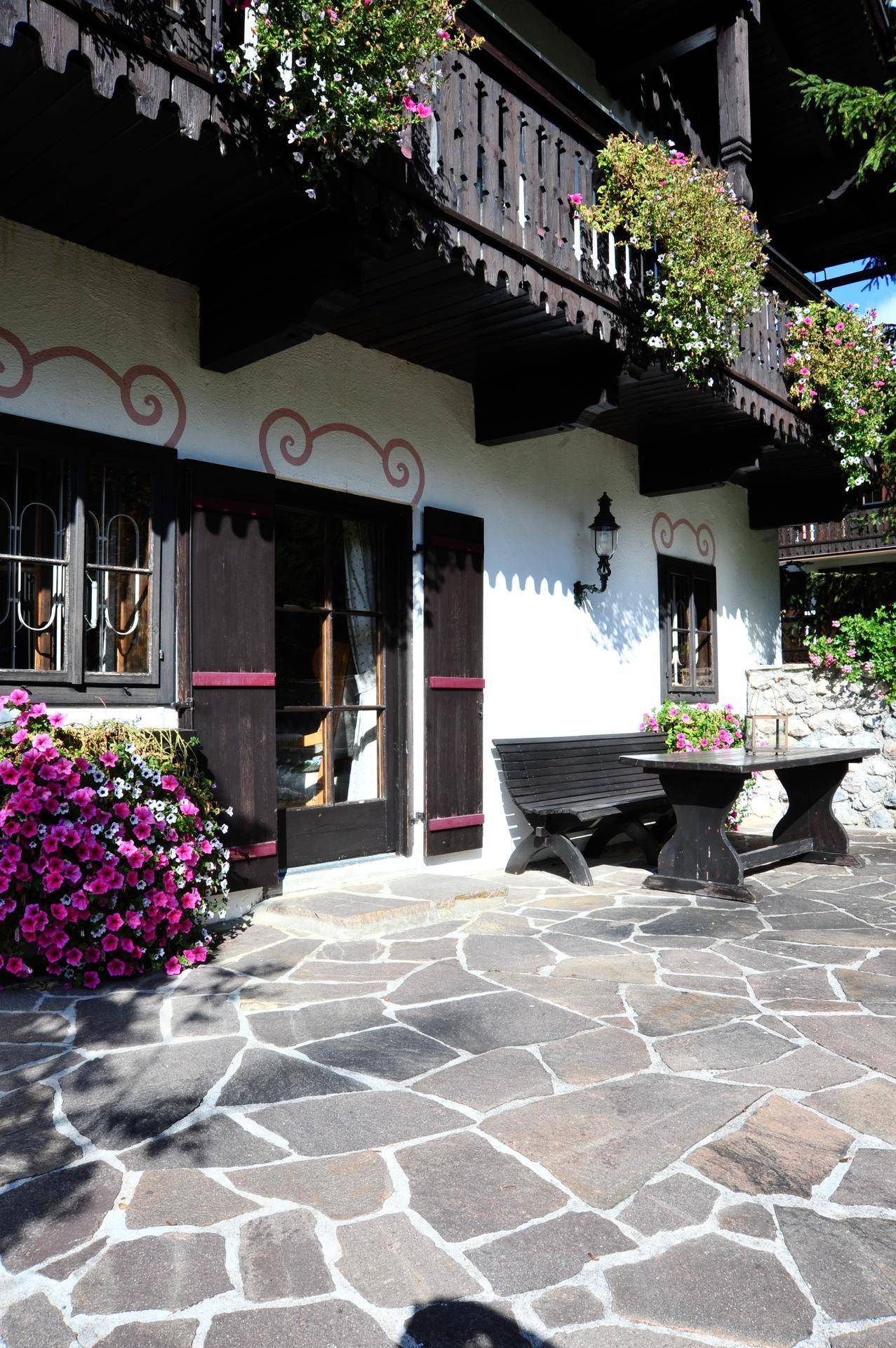 Sonniger Terrassenbereich mit rustikalen Holzmöbeln und üppigen Blumenarrangements.