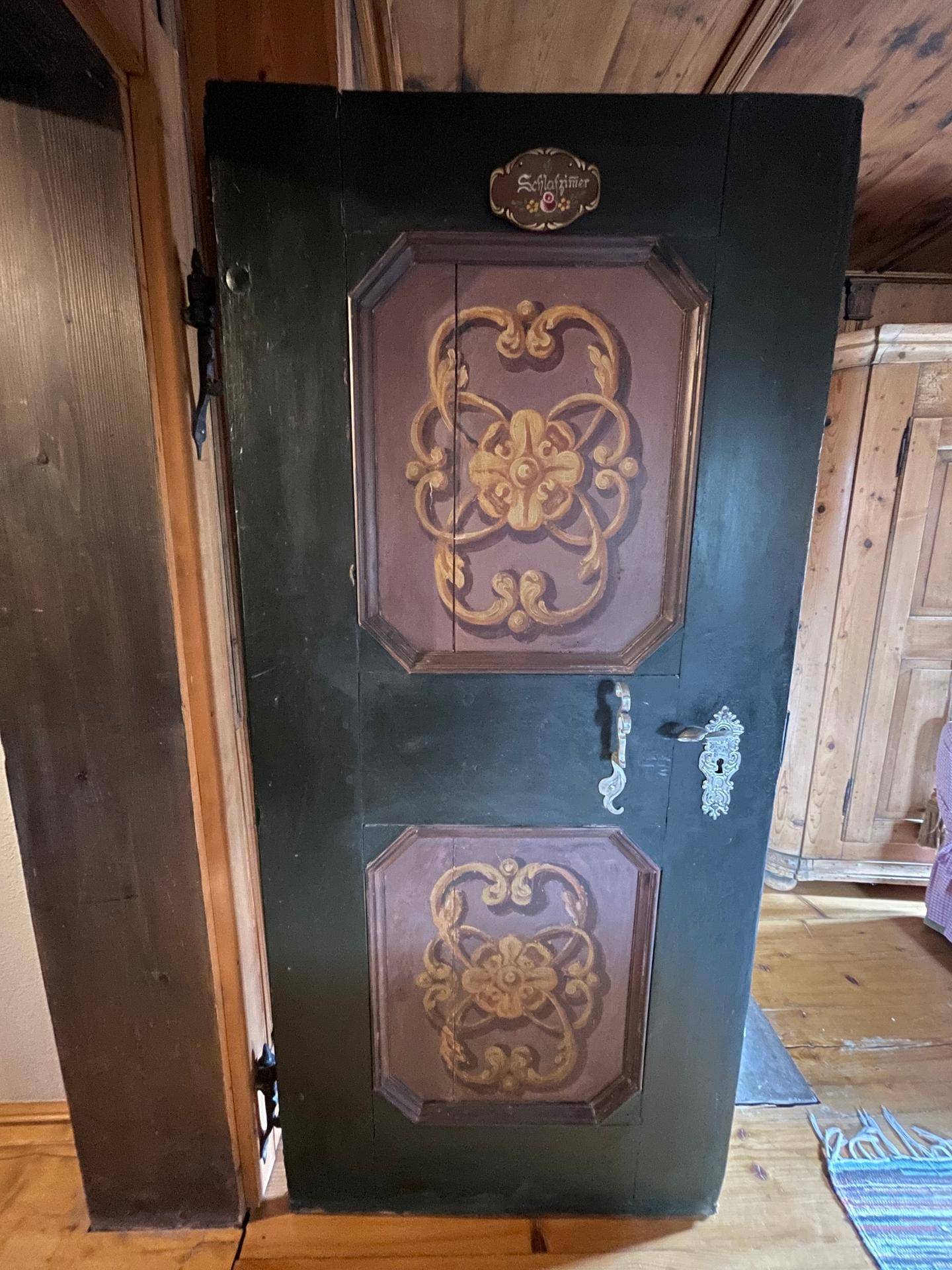 Eine kunstvoll bemalte Holztür mit traditionellen Mustern und Beschlägen.