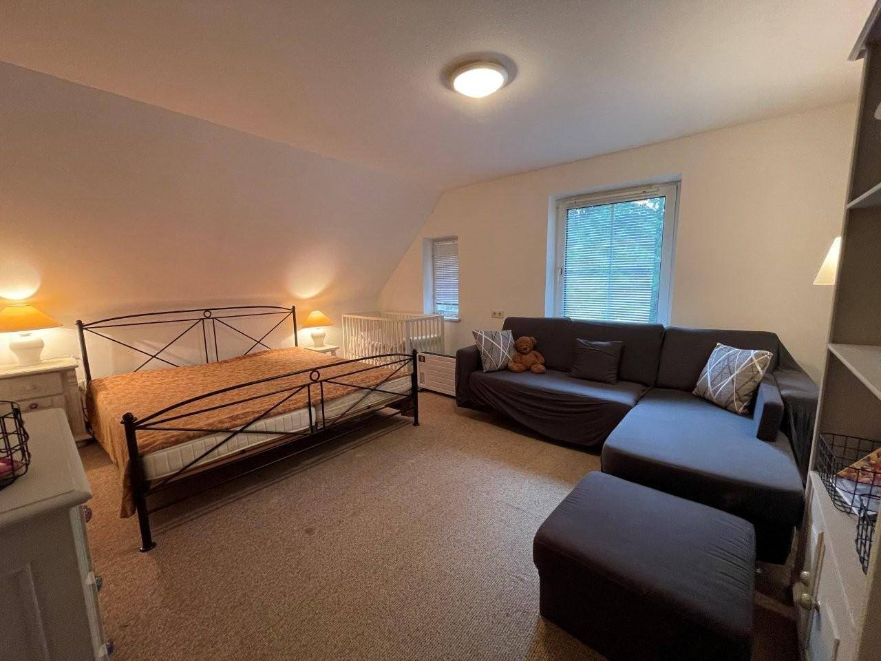 Helles Schlafzimmer im Dachgeschoss mit Doppelbett, Sofa und Dachschräge.