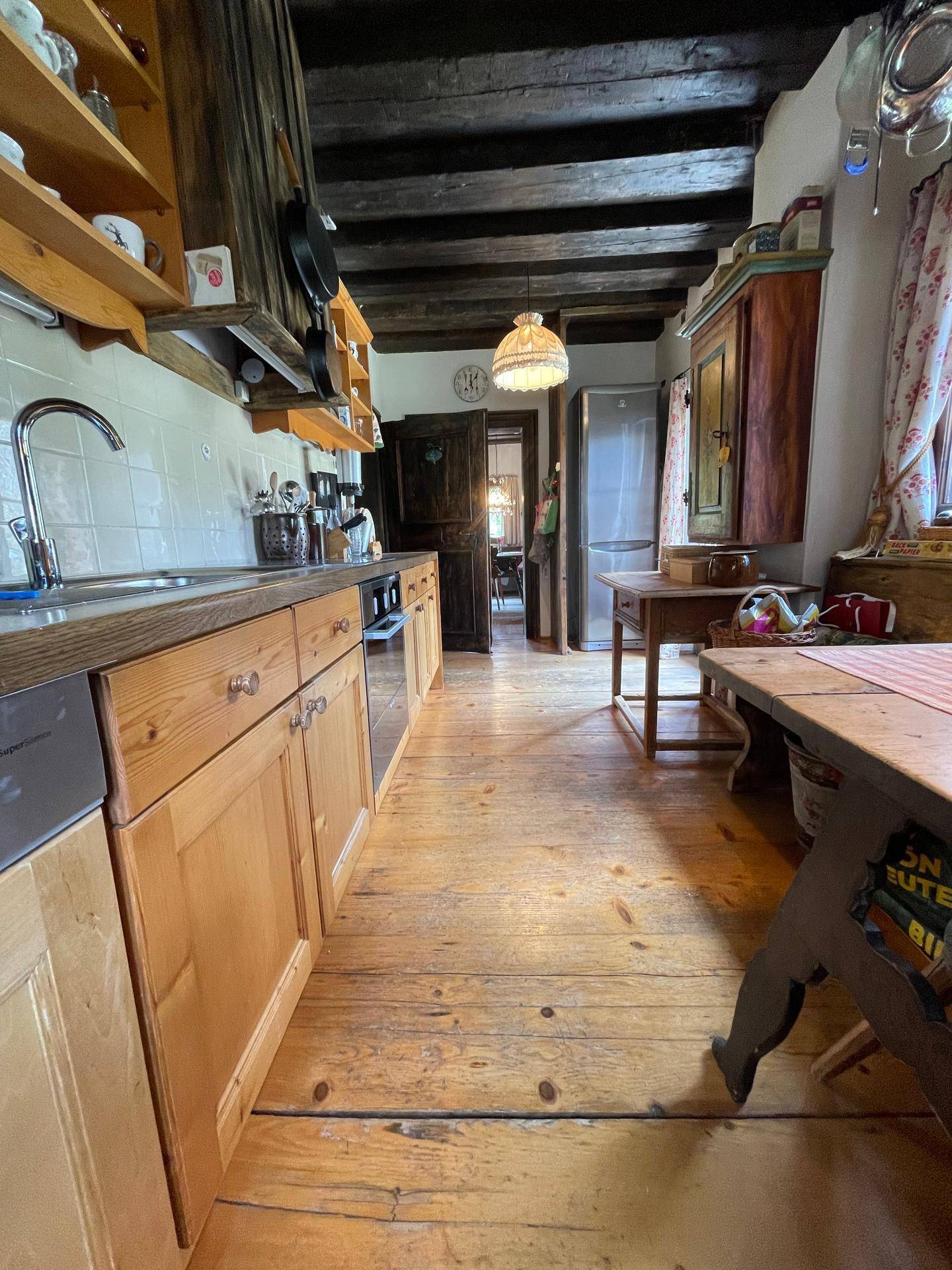 Lange traditionelle Holzküche mit Holzboden, Einbauschränken und Blick in den Flur.
