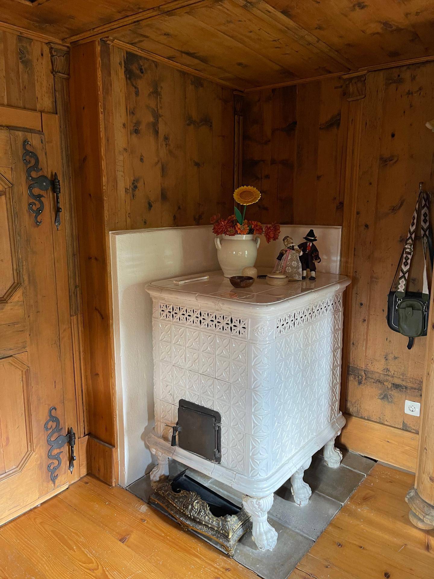 Traditioneller Kachelofen in einem Schlafzimmer mit Holztäfelung und Holzboden.