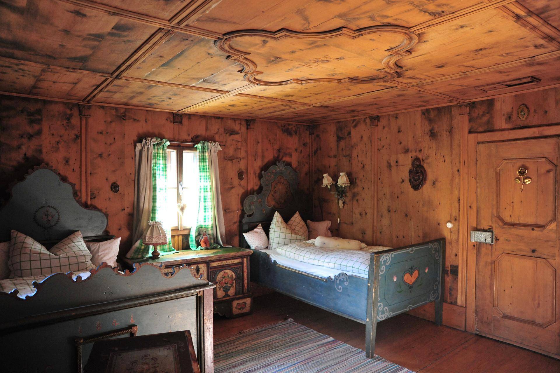 Gemütliches Schlafzimmer mit traditionellen Holzmöbeln, holzvertäfelten Wänden und Decke.