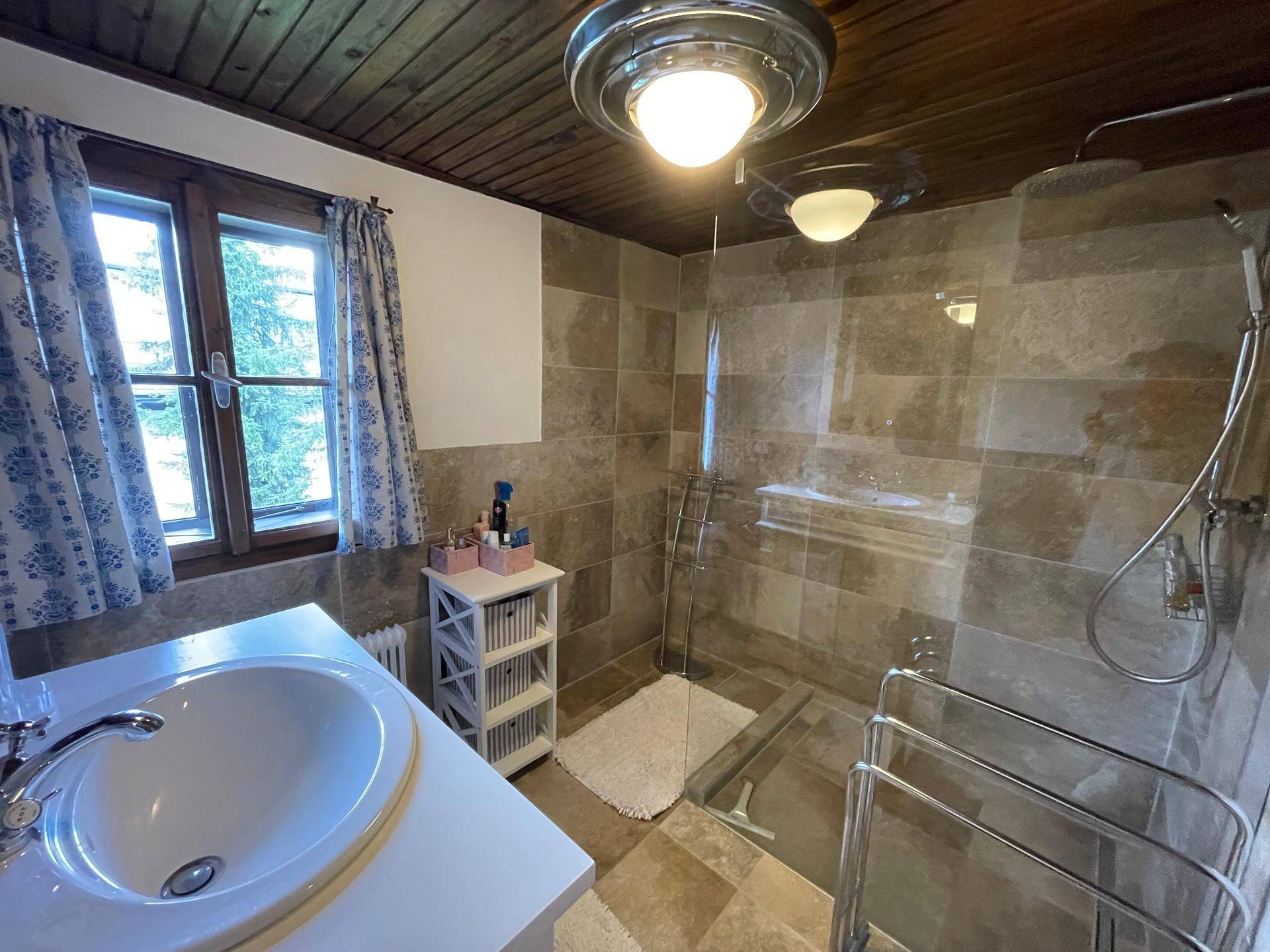 Modernisiertes Badezimmer mit begehbarer Dusche, Einzelwaschbecken und Fliesenboden.