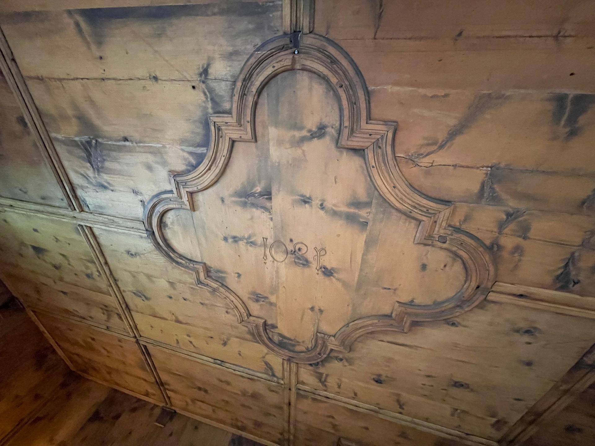 Detailaufnahme einer kunstvoll geschnitzten und verzierten Holzdecke.