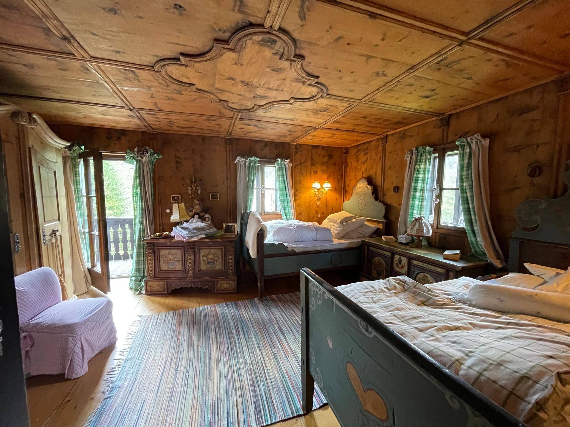 Geräumiges Schlafzimmer mit Holztäfelung, zwei Betten und Zugang zu einem Balkon.