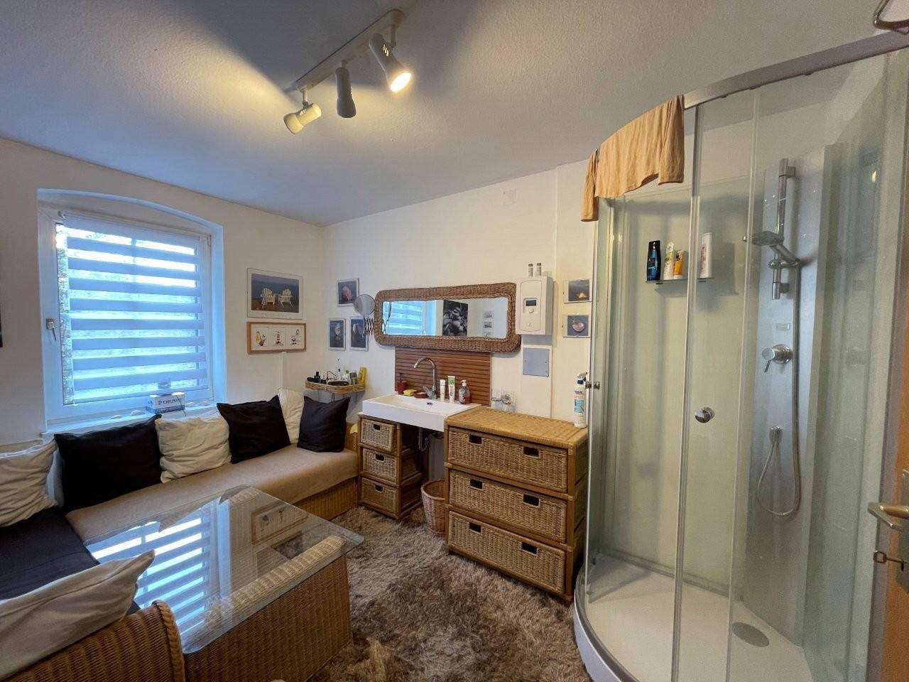 Kombiniertes Badezimmer mit Duschkabine, Waschtisch und gemütlicher Sitzecke.