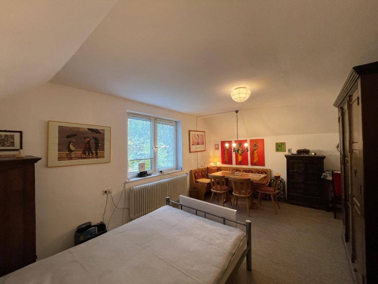 Geräumiges Schlafzimmer mit Bett, Essbereich und Blick ins Grüne.