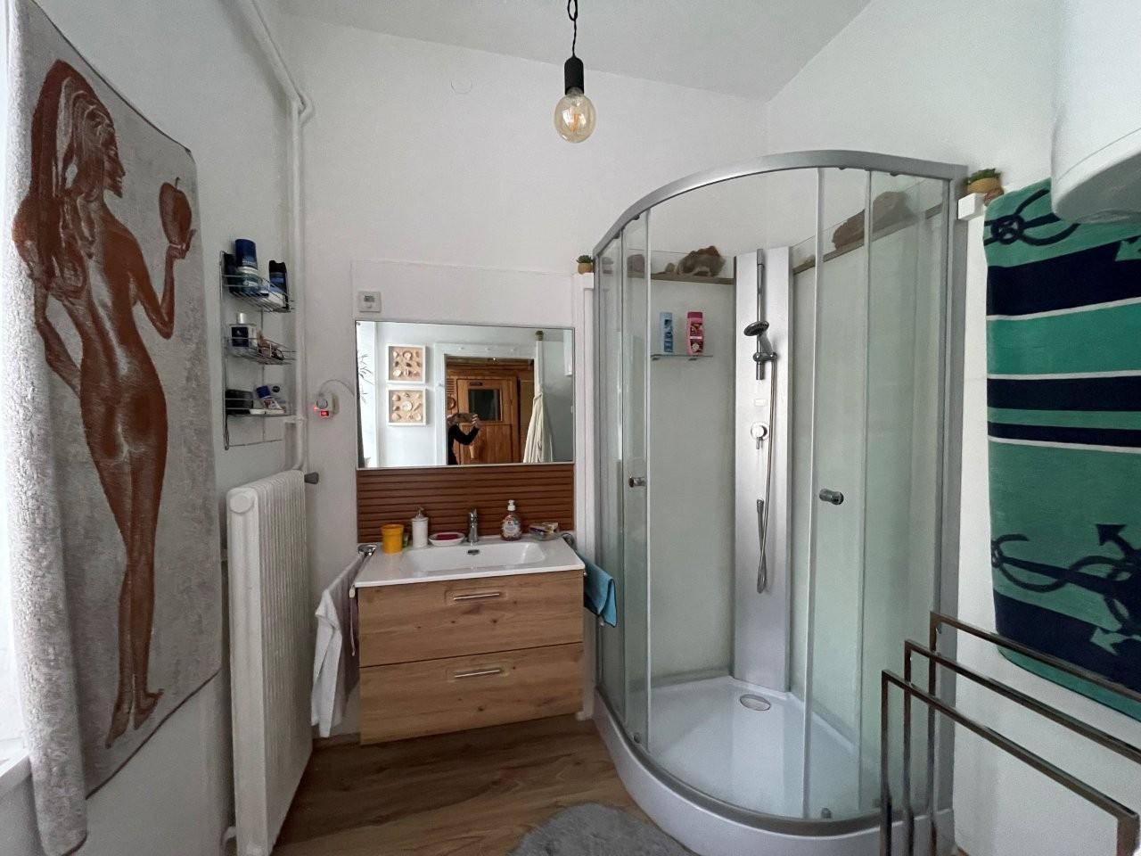 Helles Badezimmer mit moderner Duschkabine, Holzwaschtisch und Fenster.