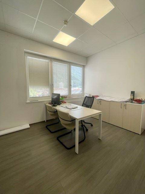 Einzelbüro mit einem Schreibtisch, zwei Stühlen und einem Fenster, das eine ruhige Arbeitsatmosphäre schafft.