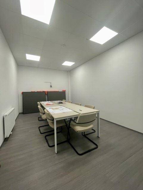 Heller Konferenzraum mit einem langen Tisch und Stühlen, geeignet für Besprechungen und Präsentationen.