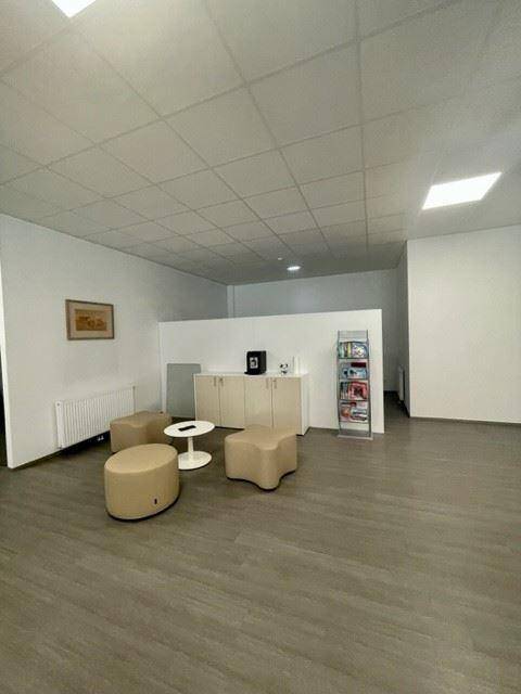 Heller Wartebereich im Büro mit bequemen Hockern und einem kleinen Tisch, ideal für Besucher.