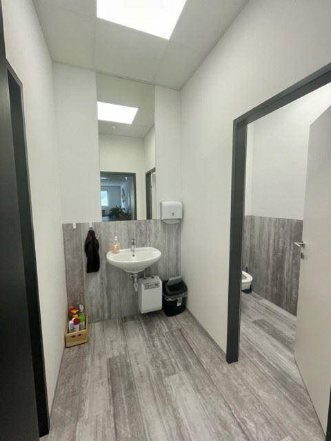 Modernes Badezimmer mit Waschbecken, Spiegel und Holzoptik-Fliesen an den Wänden.