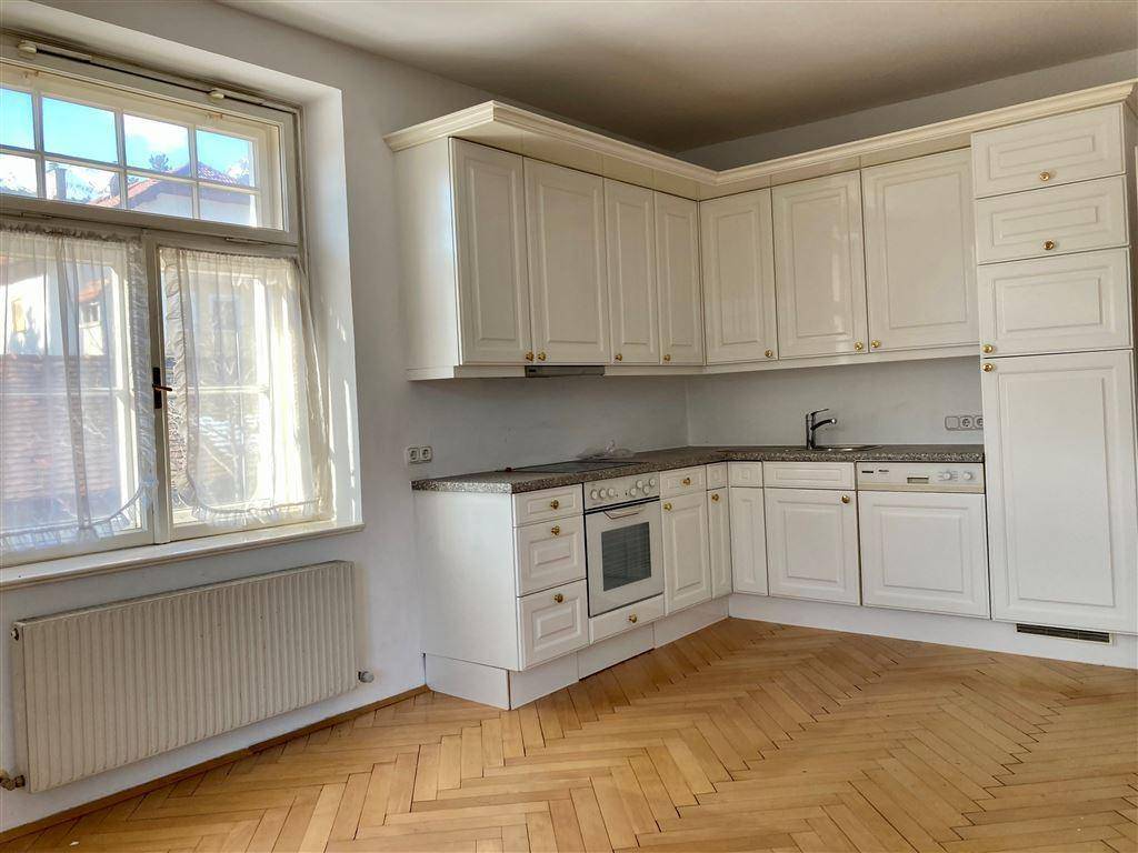Küche mit weißen Einbauschränken, Granitarbeitsplatte und großem Fenster mit viel Tageslicht.
