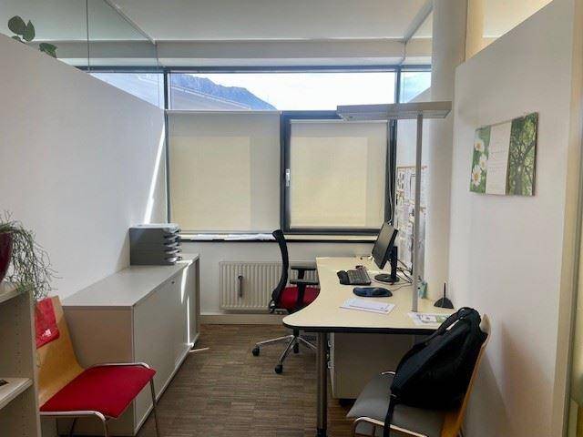 Modernes Büro mit Schreibtisch, Bürostuhl und einem Fenster mit Blick auf die Berge.