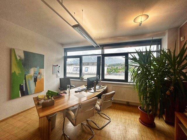 Helles Büro mit großem Schreibtisch, modernen Möbeln und weitem Blick auf die Berge.