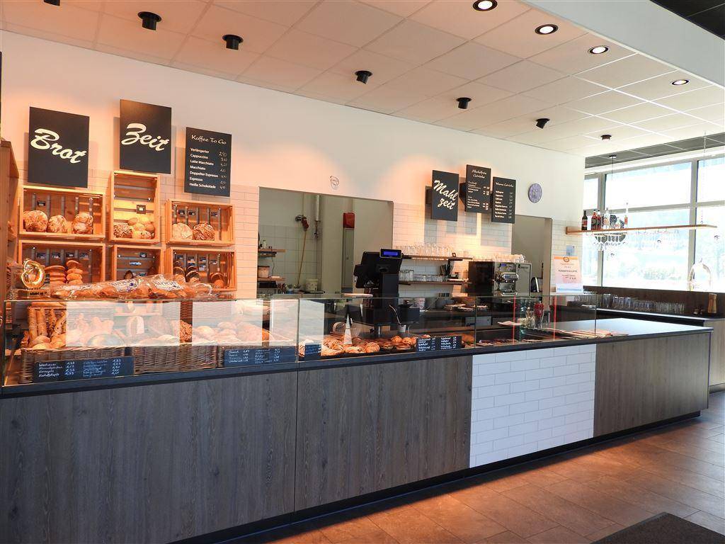 Übersichtliche Verkaufstheke einer Bäckerei mit frischen Backwaren und Preistafeln.
