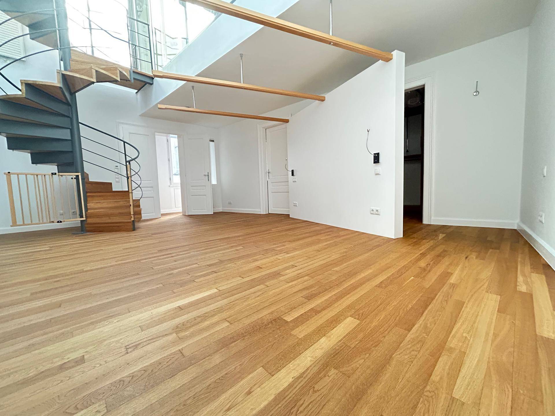 Geräumiger Wohnbereich mit Holzparkett, Wendeltreppe und offener Gestaltung.