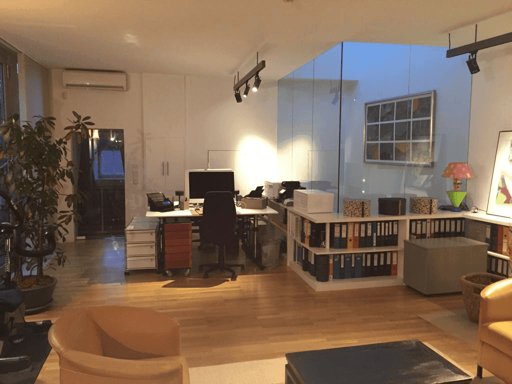 Multifunktionaler Wohn- und Arbeitsbereich mit Parkettboden und moderner Einrichtung.