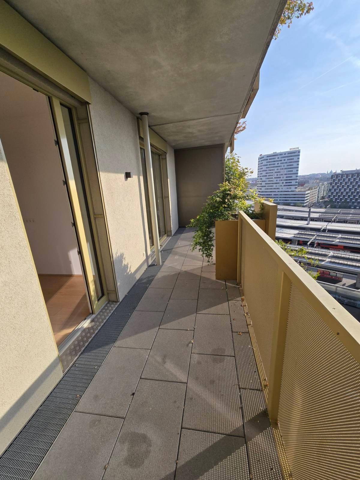 Geräumiger Balkon mit Fliesenboden und Blick auf die Stadt und die Bahngleise.