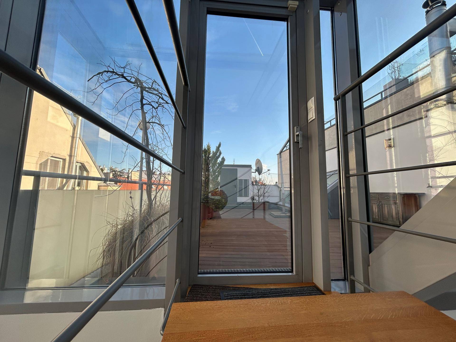Heller Treppenaufgang mit Glaswänden und Zugang zu einer Dachterrasse.