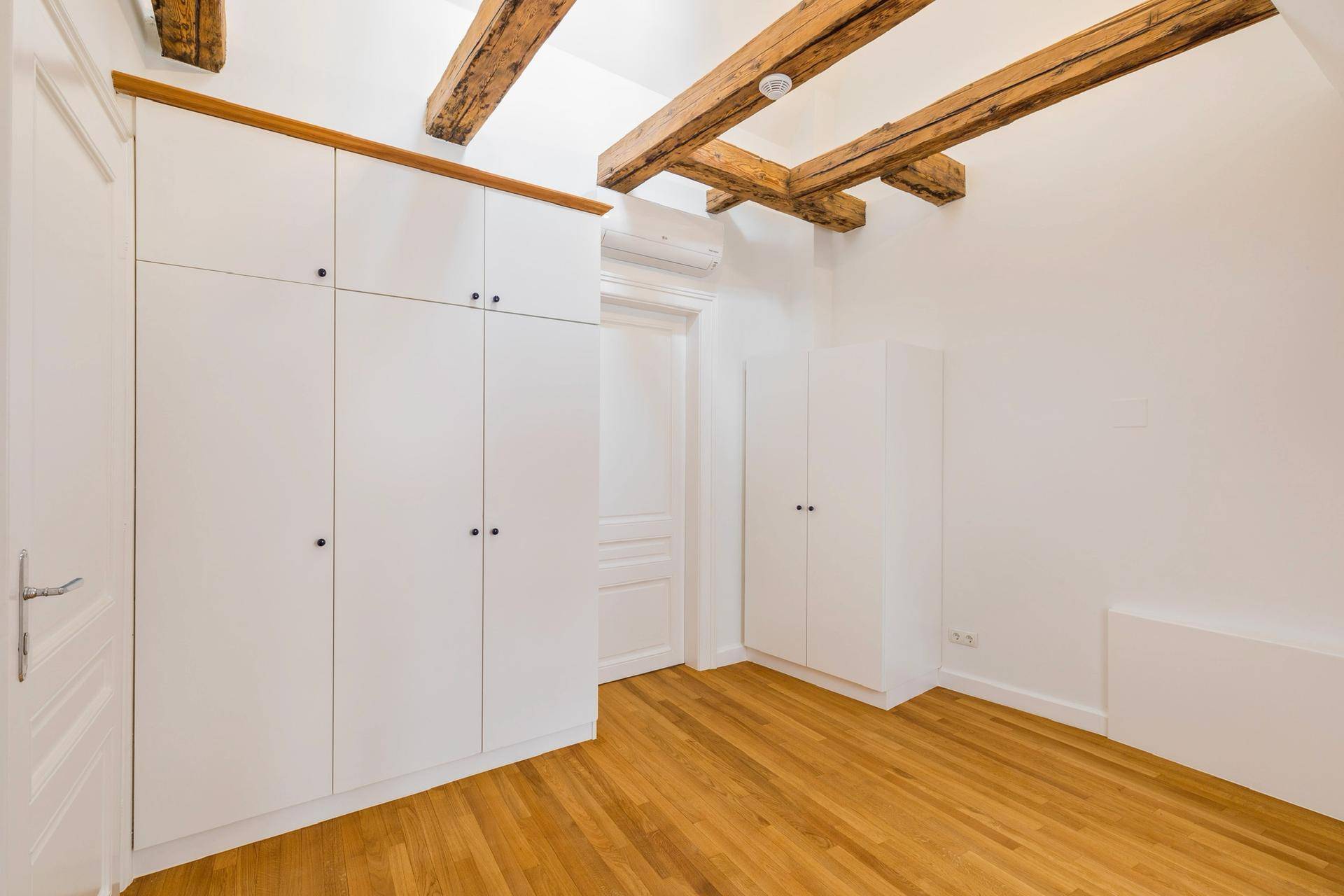 Schlafzimmer im Dachgeschoss mit Einbauschränken und sichtbaren Holzbalken.