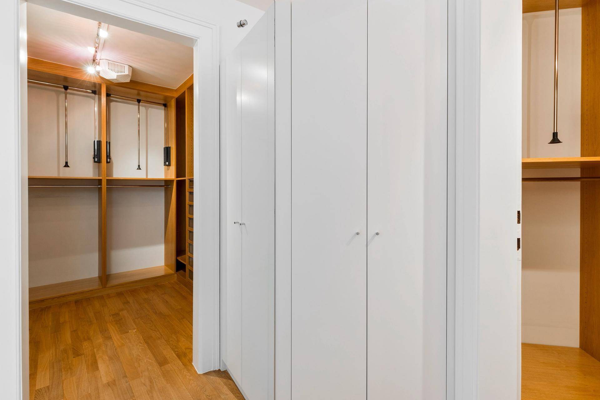 Geräumiger begehbarer Kleiderschrank mit viel Stauraum und Holzfußboden.
